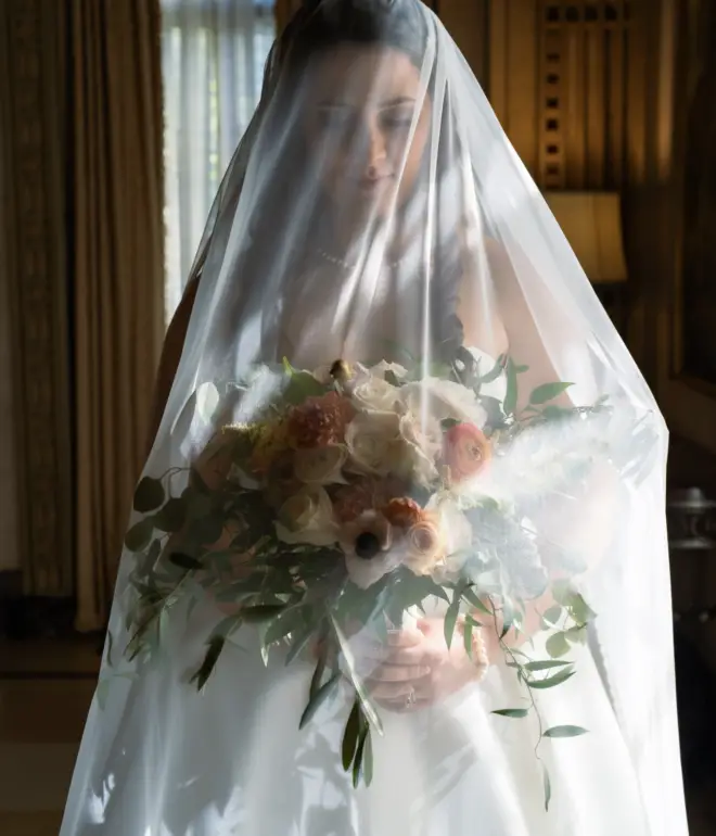 Bride under veil holding bouquet